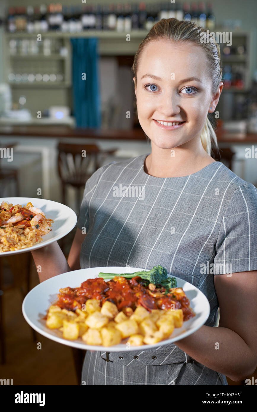 Kellnerin mit Platten aus Essen im Restaurant Stockfoto