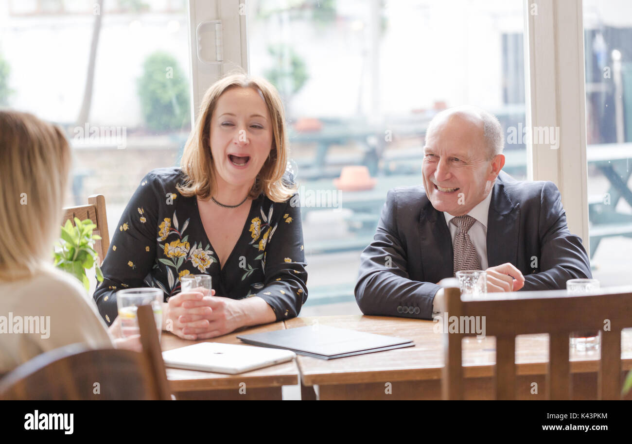 Professionelle echte Menschen, jungen erwachsenen Frau, älterer Mann, informelles Geschäftstreffen im Pub am Glas dunkles Bier. Candid unposed horizontale Schuß Stockfoto