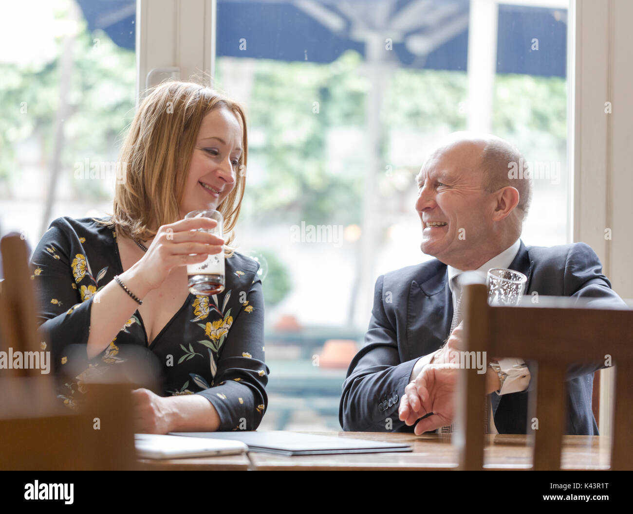 Professionelle echte Menschen, jungen erwachsenen Frau, älterer Mann, informelles Geschäftstreffen im Pub am Glas dunkles Bier. Candid unposed horizontale Schuß Stockfoto