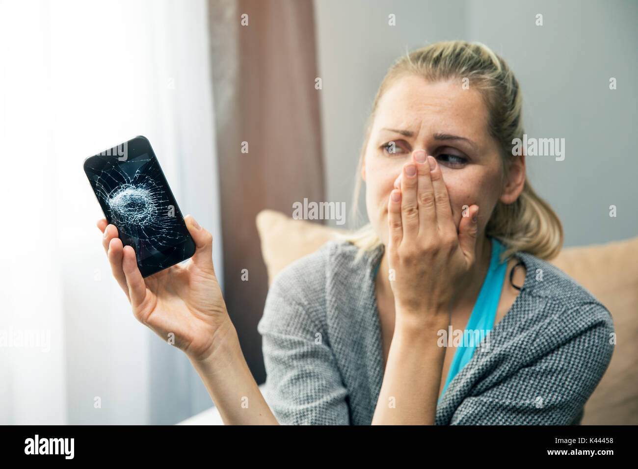 Traurige Frau mit smart phone mit defekten Bildschirm in der Hand Stockfoto