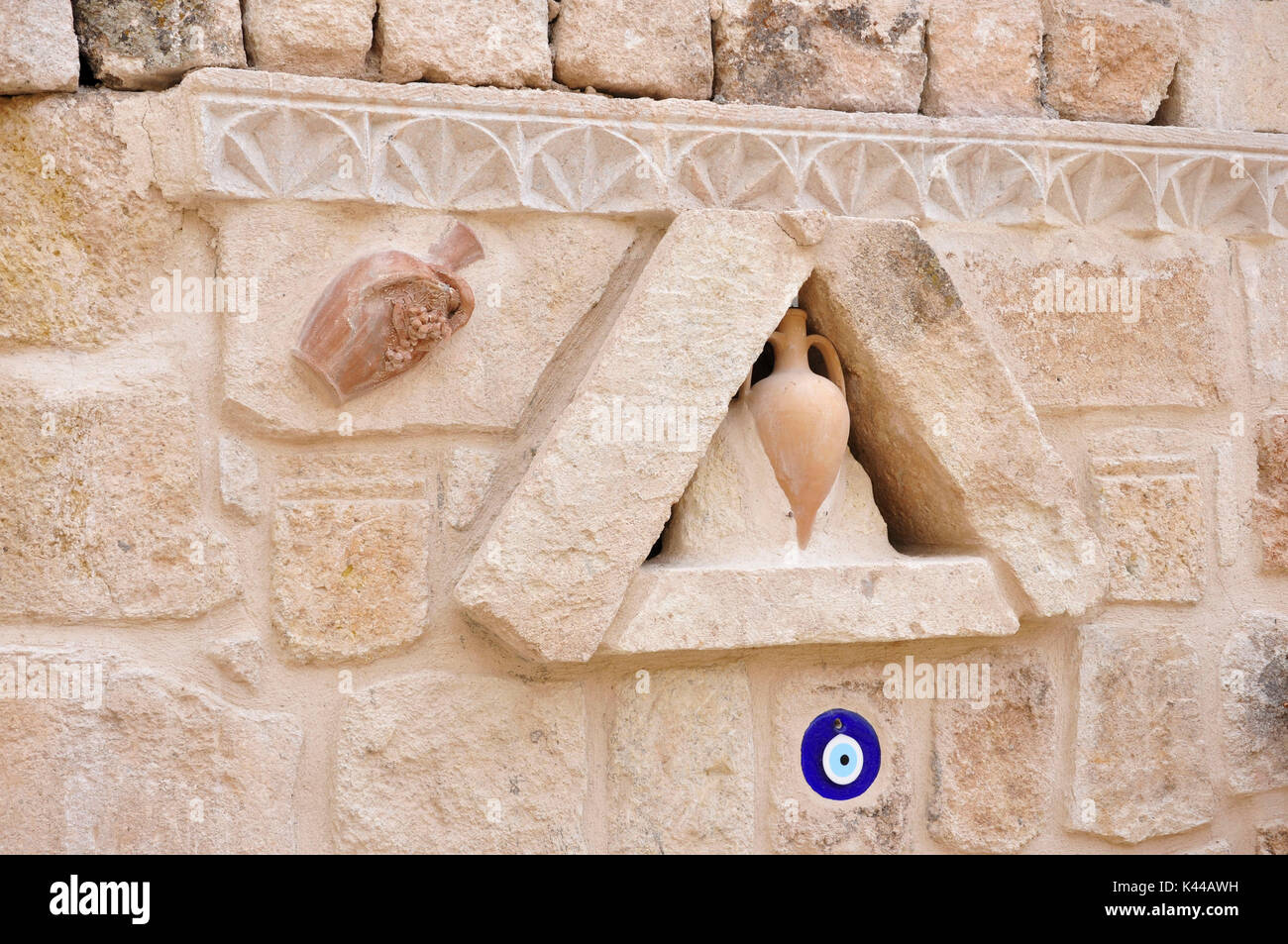 Typische Skulptur an der Wand auf die alten Häuser der Kappadokia Region in der Türkei. In diese Skulptur sind die "Töpferei", die Vasen aus Terrakotta und in blauer Farbe die Allah Auge dargestellt. Die Allah Auge hat das Ziel, zu schützen. Stockfoto
