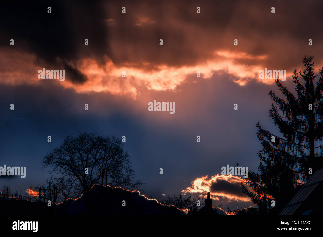 Hintergrundbeleuchtung Wolken leuchtende Orange gegen einen dunklen blauen Himmel Stockfoto