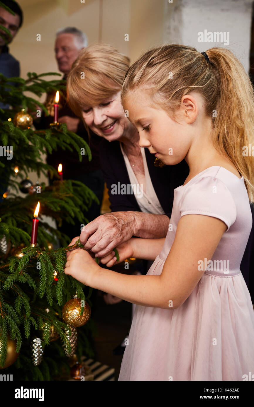 Kind mit Großeltern schmücken Weihnachtsbaum, halb Portrait Stockfoto