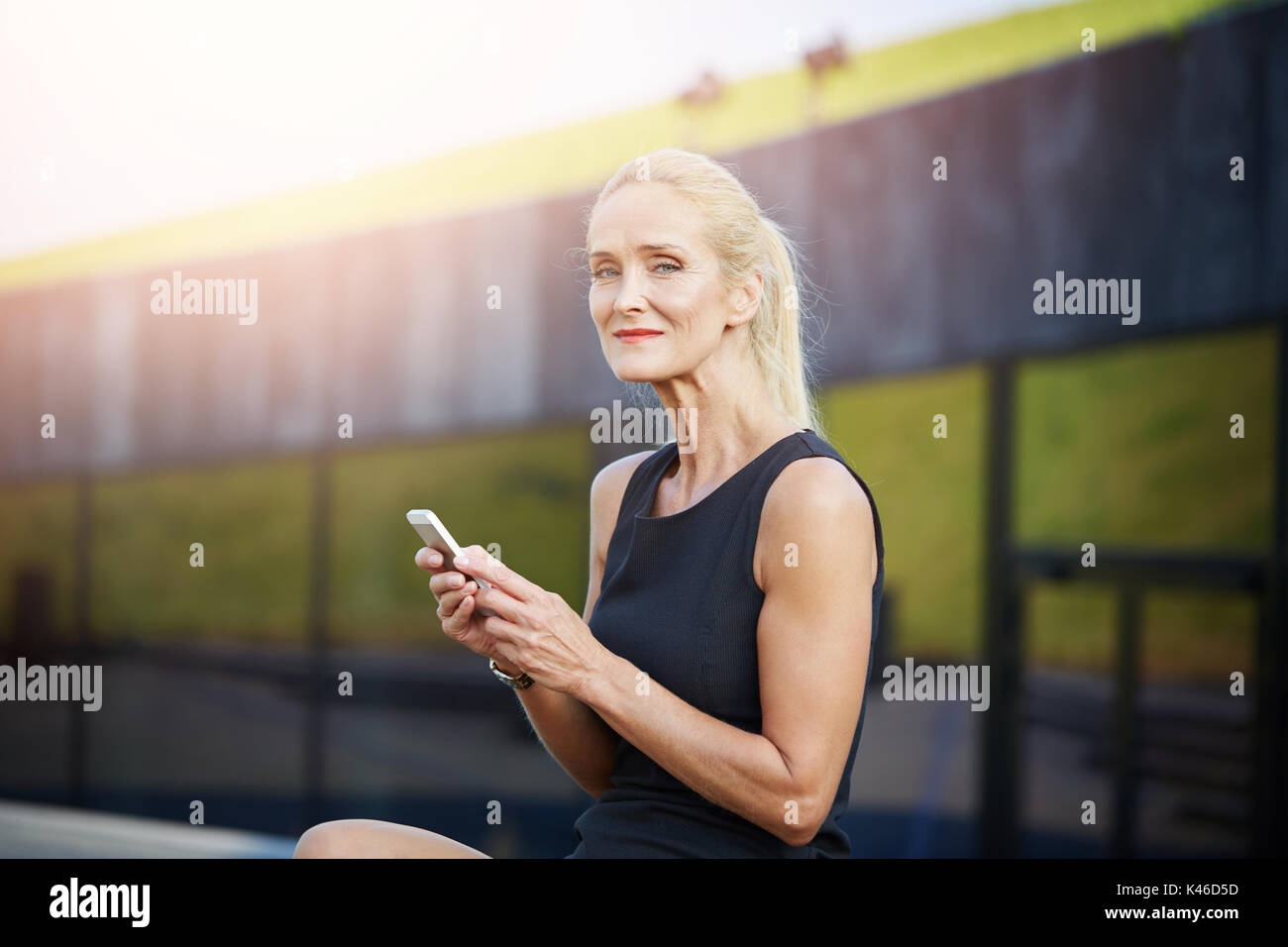 Portrait von Inhalten Geschäftsfrau, draußen sitzen und die Verwendung von Mobile. Stockfoto