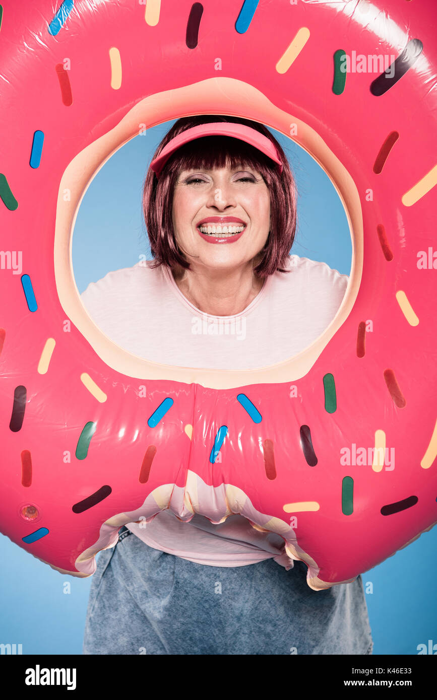Lächelnde ältere Frau mit float Ring in Form von donut Stockfoto