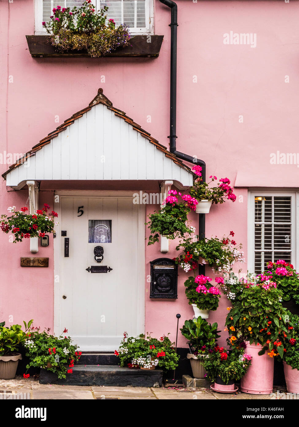 Ein rosa Haus mit bunten Blumen in Dunster High Street in der Nähe von Minehead, Somerset. Stockfoto