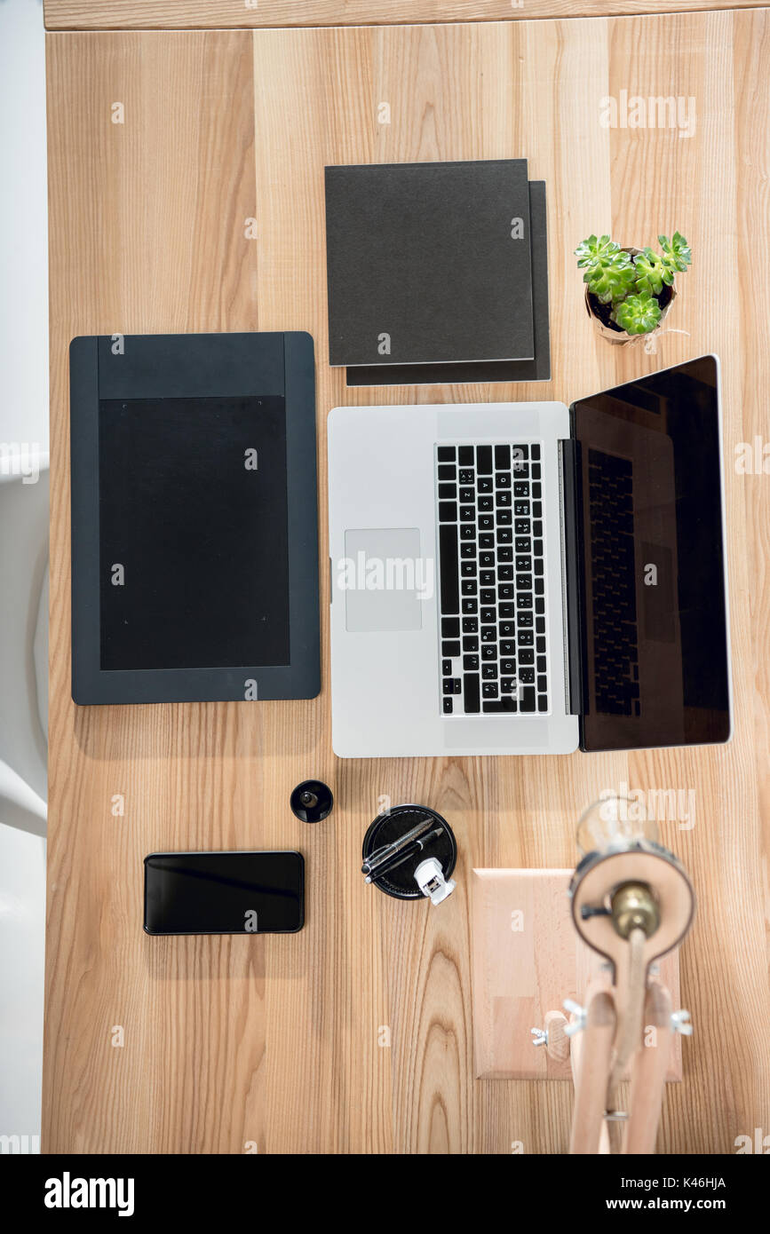 Blick von oben auf die Laptop mit Grafiktablett und Smartphone auf  hölzernen Tischplatte im Büro Stockfotografie - Alamy