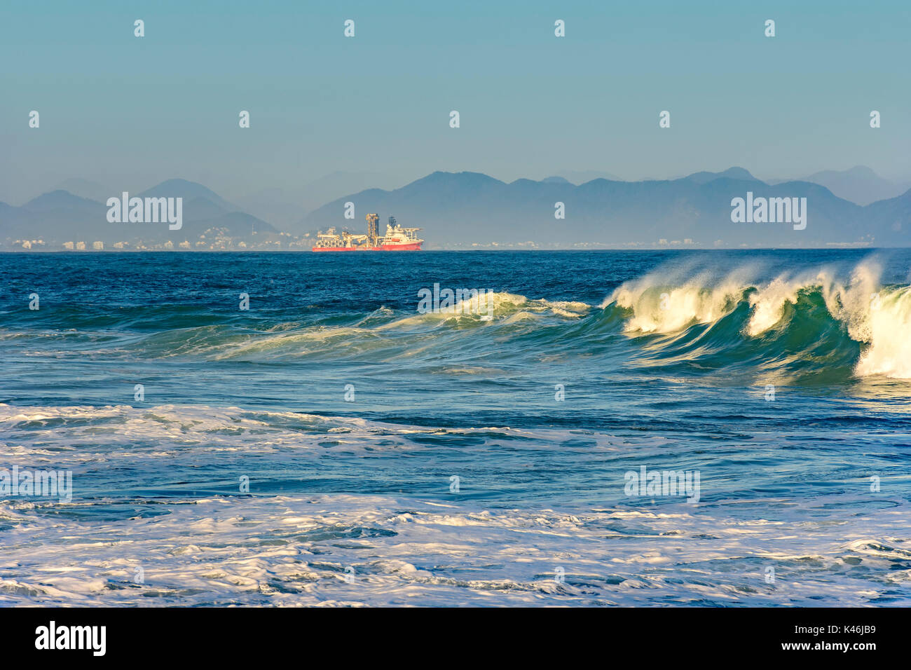 Schiff segeln zwischen den Inseln, Hügel und Wellen mit Stadt im Hintergrund Stockfoto