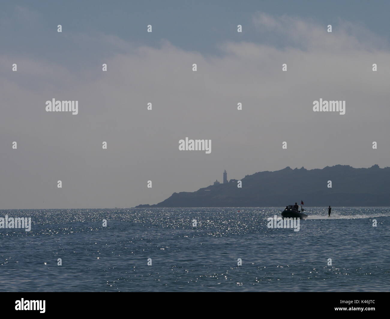 Eine weibliche waterskiier und Speed Boot auf dem Meer, mit Startpunkt Leuchtturm im Hintergrund, in South Devon Stockfoto