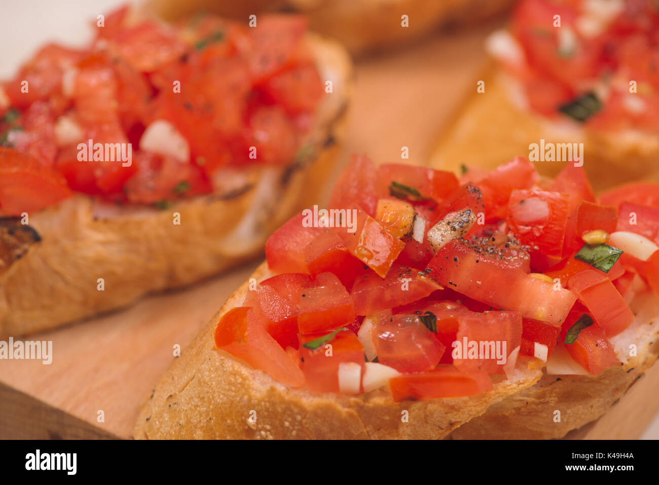 Leckere italienische Bruschetta mit Brot mit Tomaten und Kräutern auf Holzbrett gekrönt Stockfoto