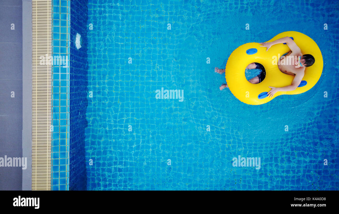 Luftaufnahme, ein Mann, der gelbe Pool schwimmen, am Pool im Sommer entspannen Stockfoto