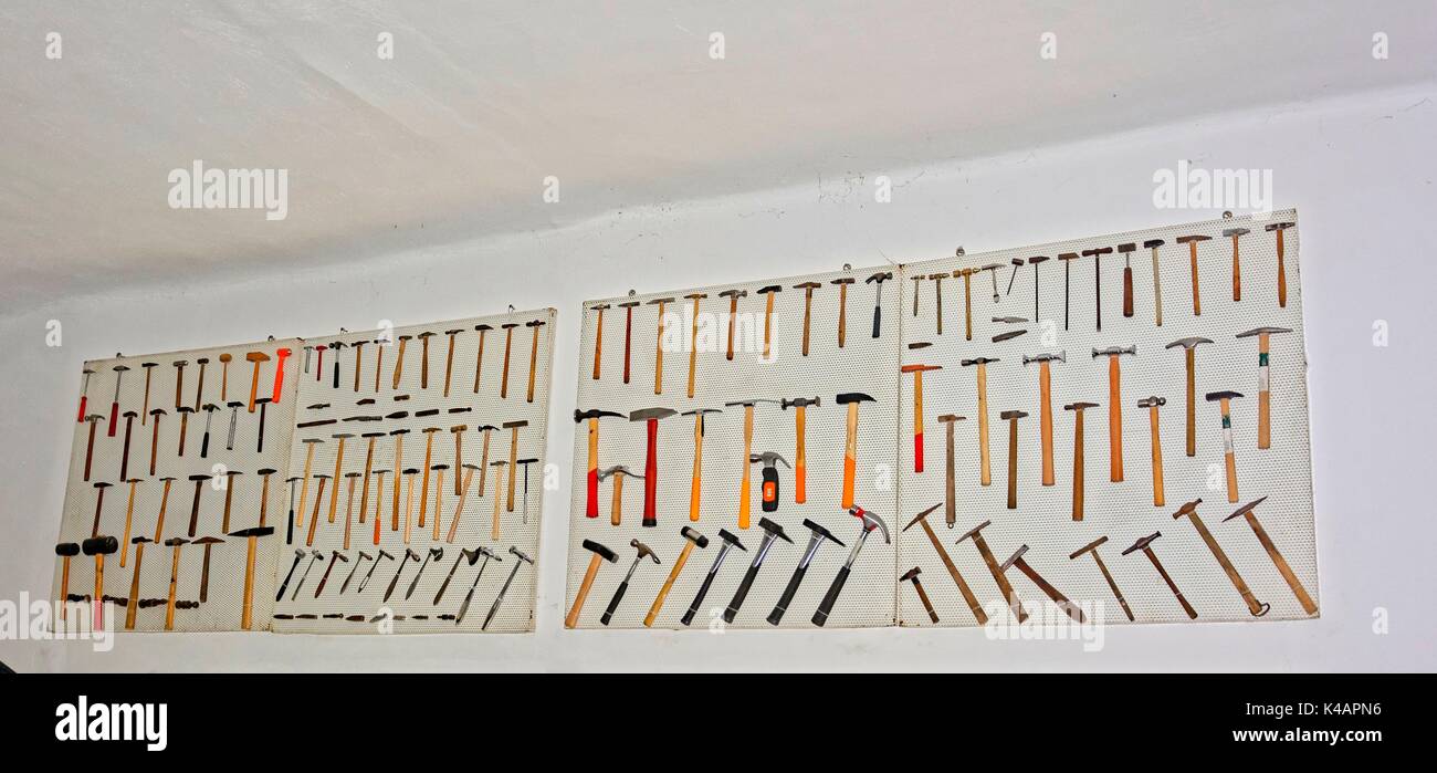 Verschiedene Hämmer hängen an einem Werkzeug Loch Wand, Lochblech Stockfoto