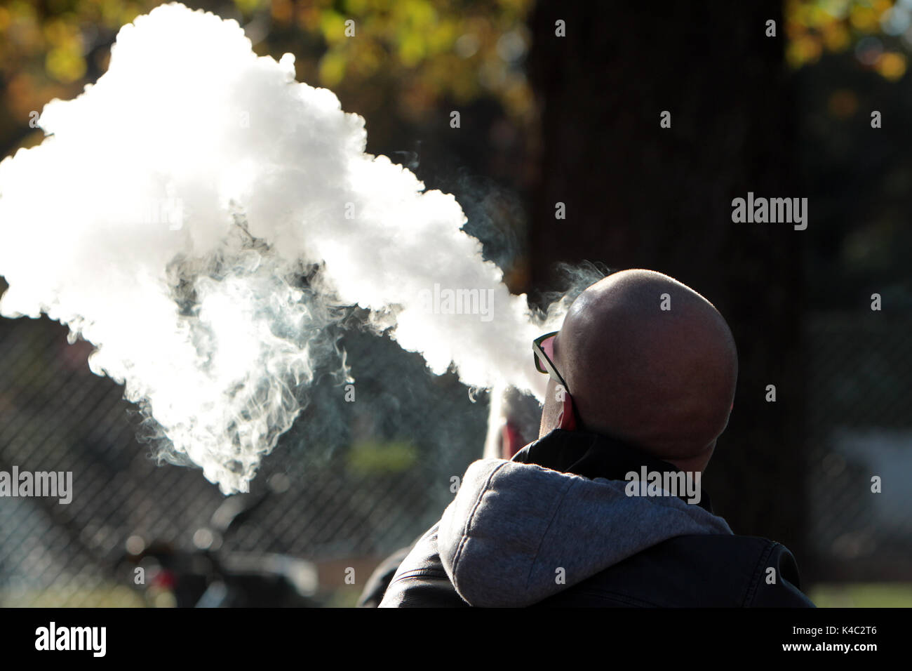 Raucher atmet EINE riesige Rauchwolke aus seiner E-Zigarette aus Stockfoto