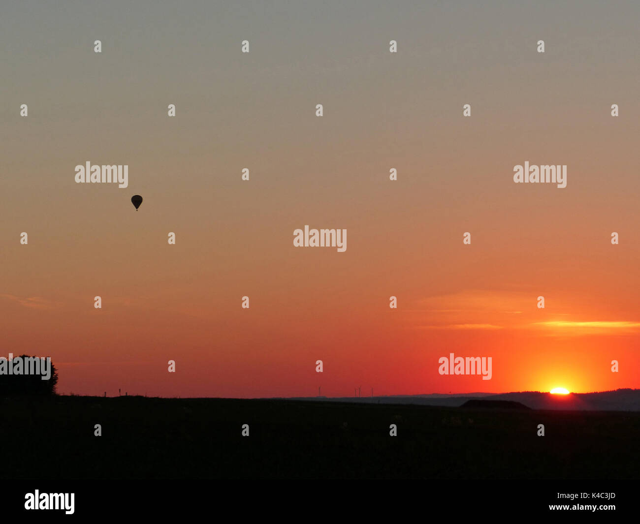 Sonnenaufgang über Franken mit einem Heißluftballon, Treibt in der Ferne Stockfoto