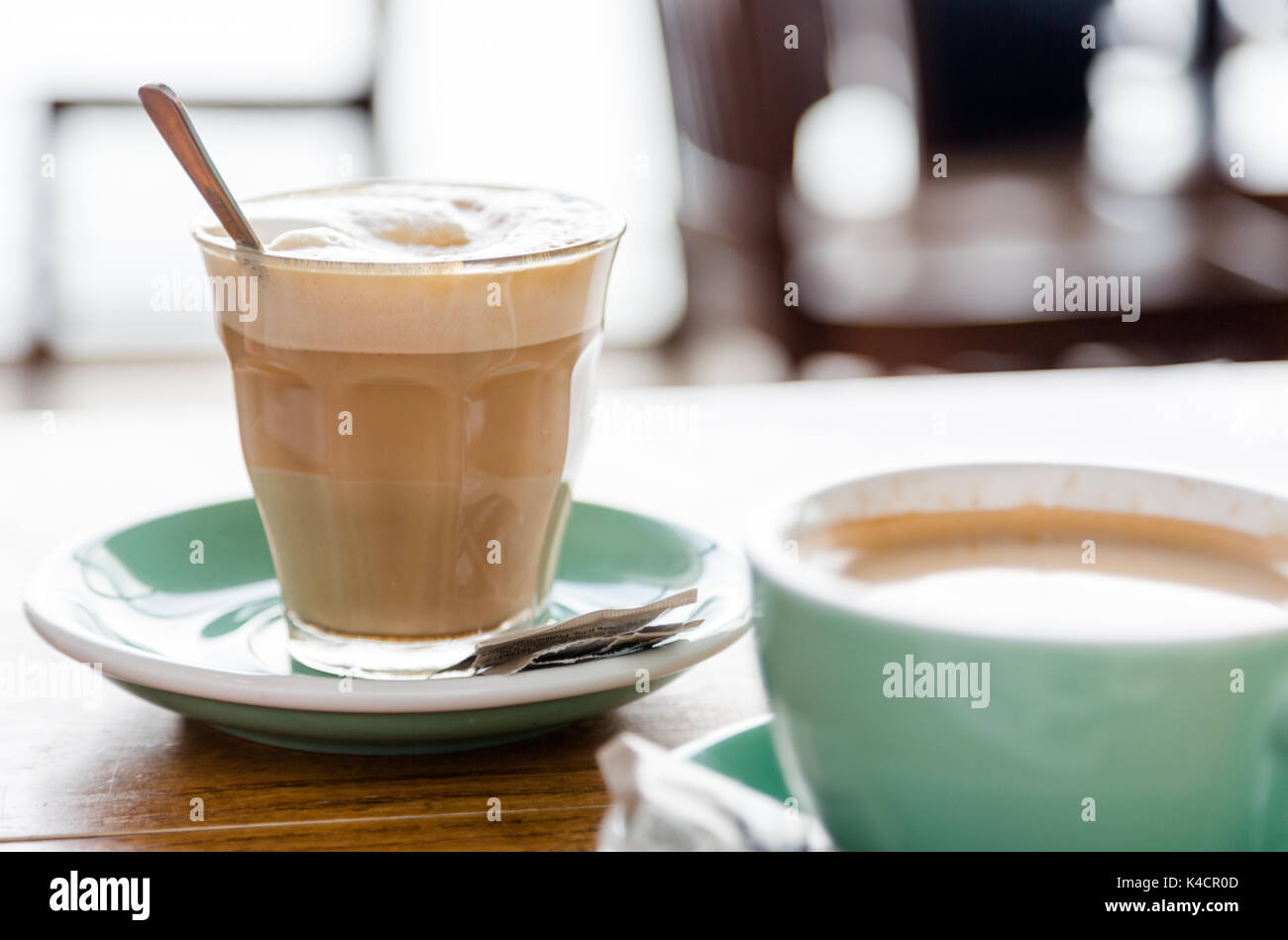 Weiß Kaffee in transparentretro Glas auf grün Topf und hölzernen Tisch in bar. Ein guter Start in den Tag. Close up natürliches Licht Erntegut Stockfoto