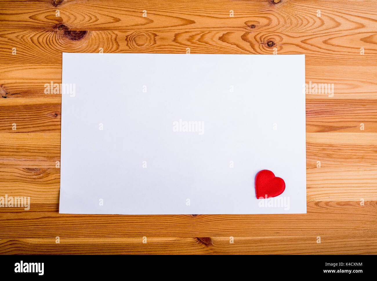 Layout mit leeren Blatt Papier auf Holz- Oberfläche mit kleinen roten Herzen kostenlose Kopie. Stockfoto