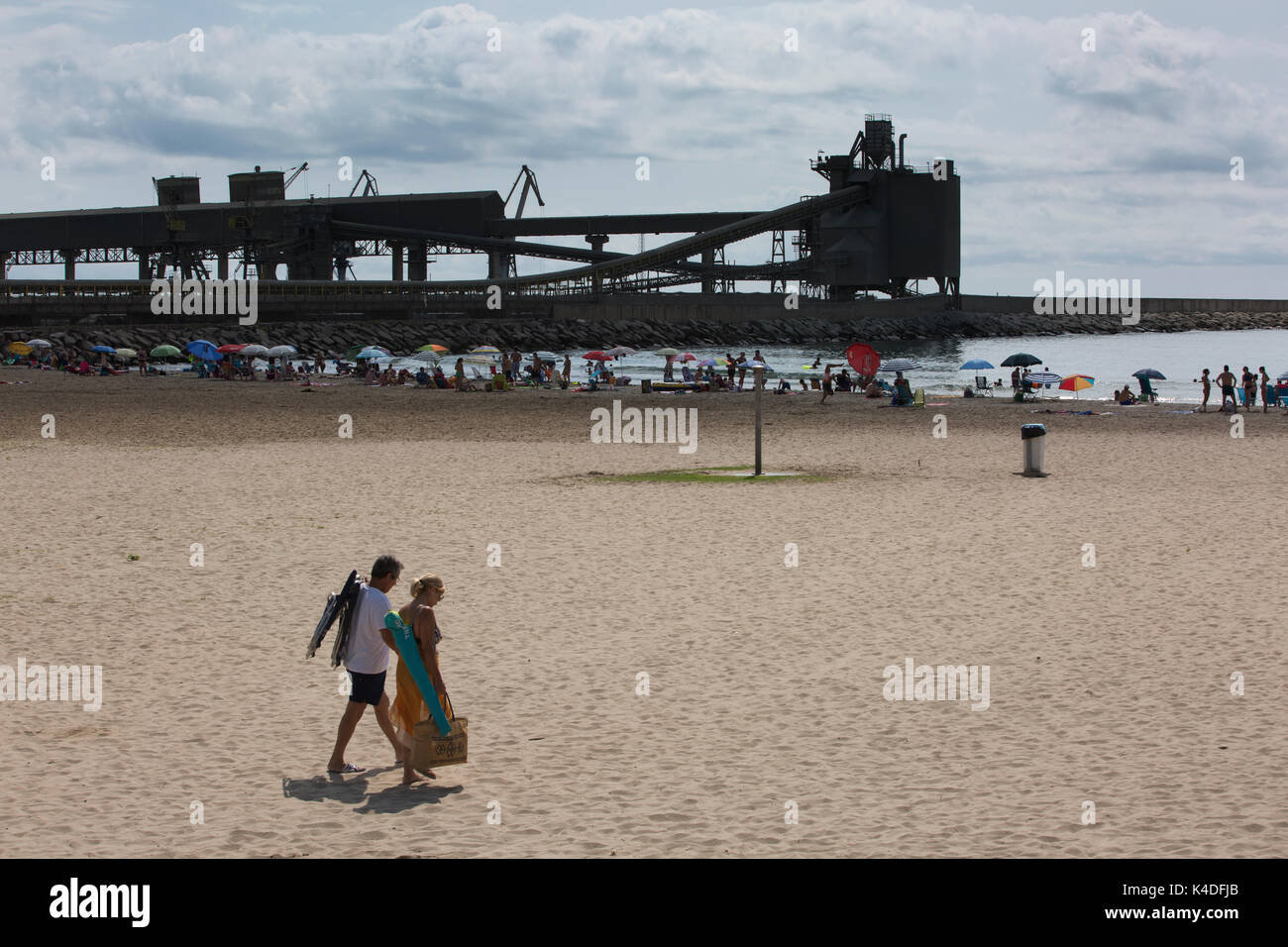 Urlauber genießen den Sommer am Strand von Port of Alcanar, von Cemex Zementwerk Industriegebäude, Alacanar, Tarragona, Spanien übersehen Stockfoto