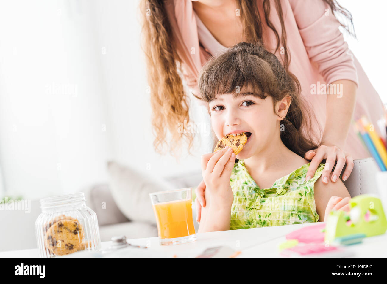 Cute Vorschule Mädchen einen Snack mit ihrer Mutter, sie ist Essen einige leckere Cookies, Ernährung und Lifestyle Konzept Stockfoto