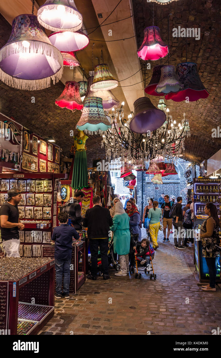 Die Menschen sammeln sich um Stände im Pferd Markt in Camden Market in Camden Town, London. Hellen Farben hängen von der Decke. Stockfoto