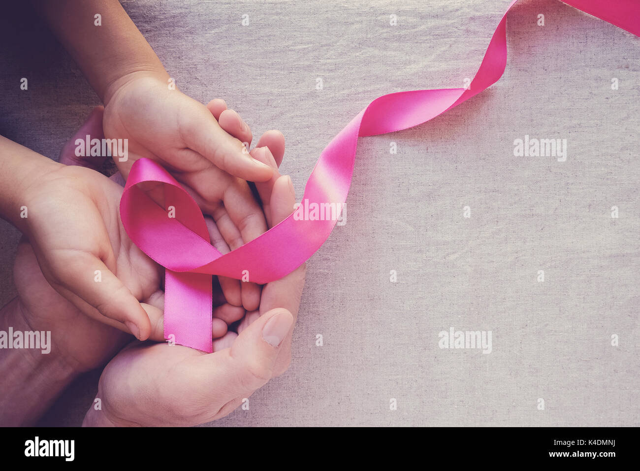 Erwachsener und Kind Hände halten rosafarbenen Bändern, Brustkrebs-Bewußtsein, Abdominal-Bewußtsein und Oktober rosa Hintergrund Stockfoto