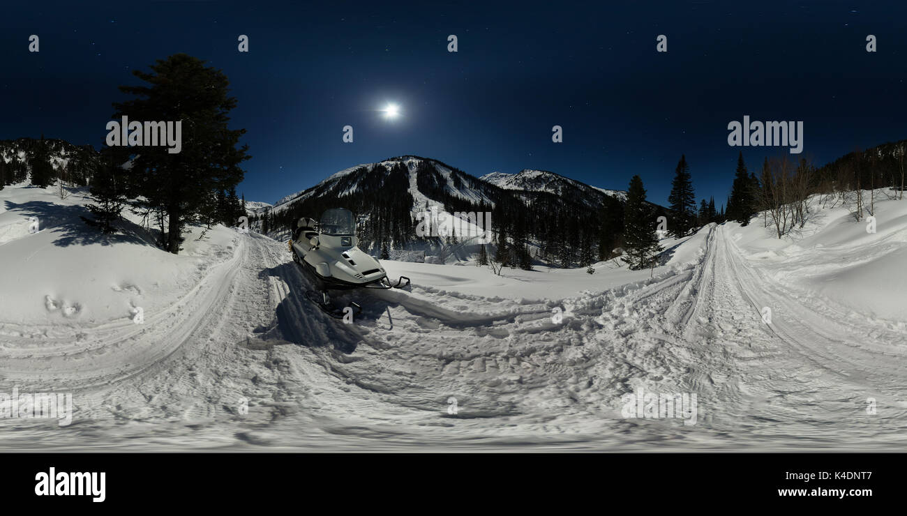 Schneemobil in einer mondhellen Nacht auf der Straße in den Bergen. Sphärische 360 180 Panorama. Stockfoto