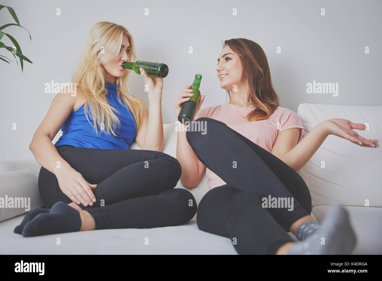 Portrait von Frau sitzt bequem auf der Couch Bier trinken und hören auf ihre Freundin. Stockfoto
