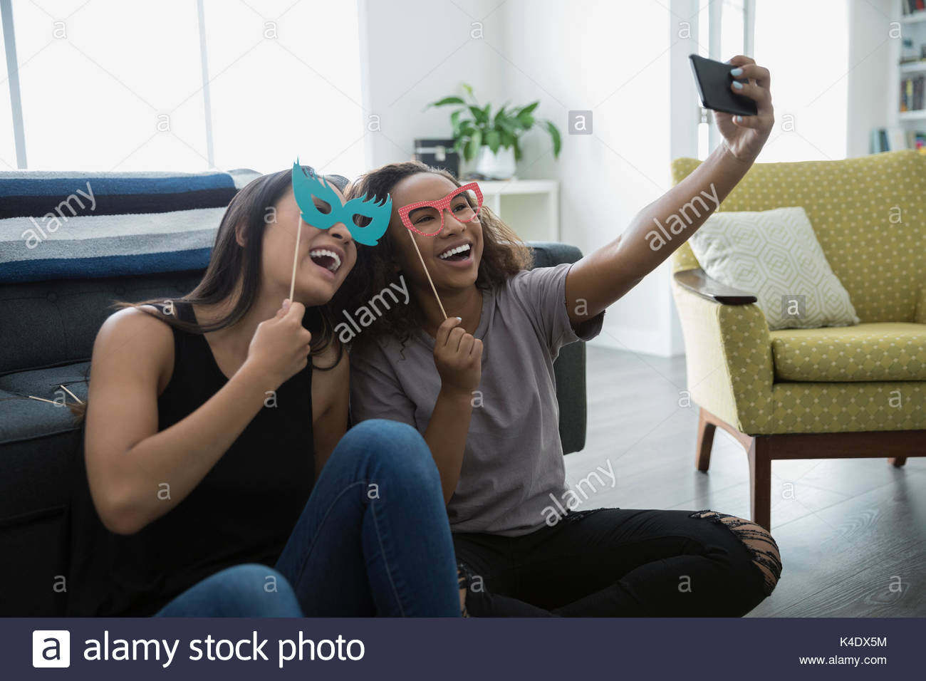 Teenage girl friends mit prop Brillen und Augenmaske, wobei selfie im Wohnzimmer Stockfoto