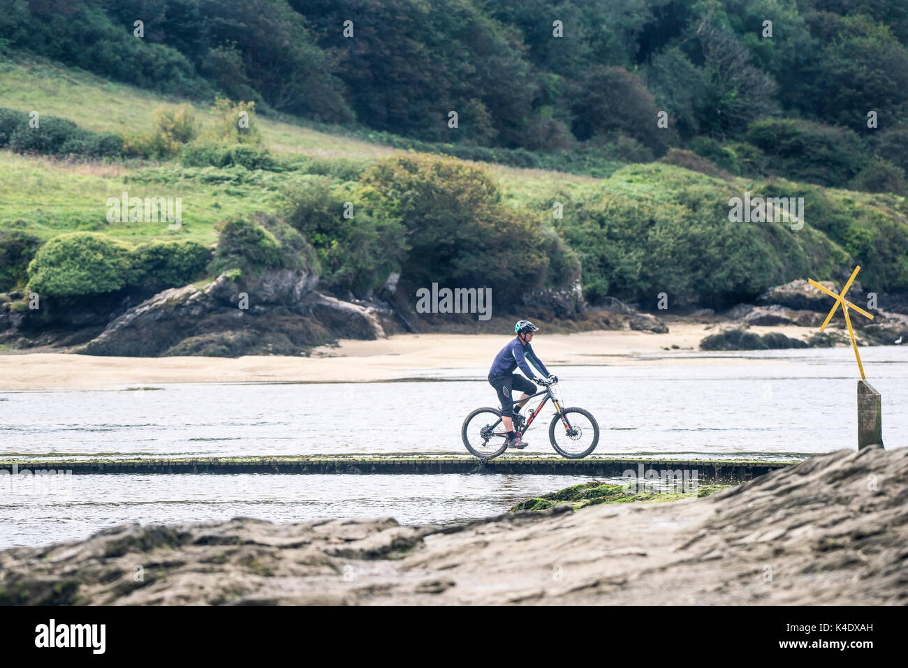 Gannel Mündung - ein Mann, ein Mountainbike über den Fluss Gannel über einen Steg bei Ebbe. Stockfoto