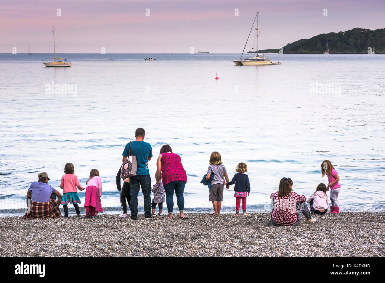 Trebah Garden Beach - Erwachsene und Kinder stehen an der Küste am Strand von Trebah Garten in Cornwall. Stockfoto