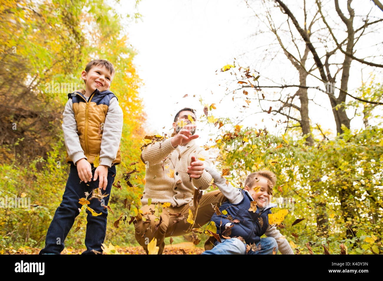 Junger Vater mit seinen Söhnen im herbstlichen Wald. Stockfoto