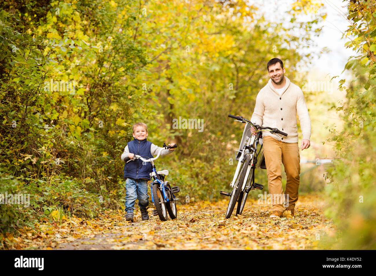 Vater mit kleinen Sohn Radfahren im Herbst Park. Stockfoto
