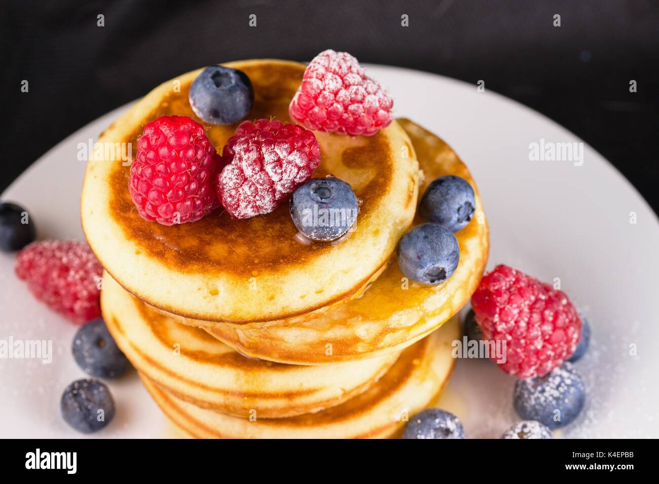 Puderzucker überzogen Himbeeren und Blaubeeren in Sirup auf Pfannkuchen Stapel Stockfoto