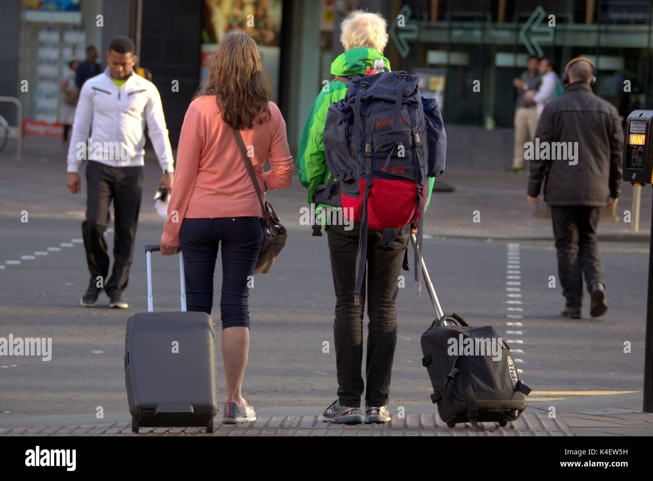 Glasgow street scene amerikanische Touristen Kreuzung kröte an Ampeln mit Trolley und Rucksack Stockfoto
