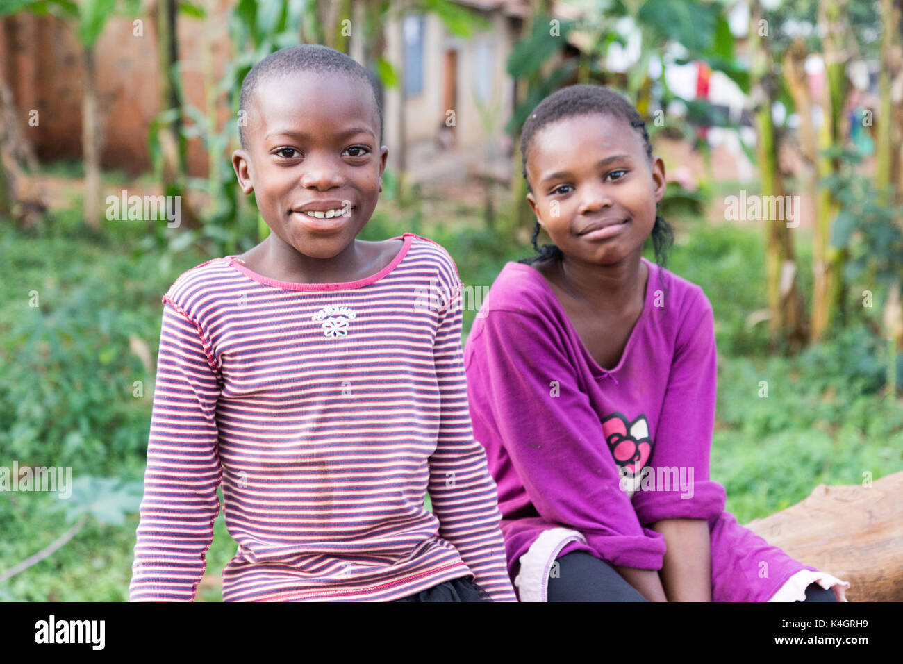 Zwei nette junge Mädchen lächelnd und sitzen auf einen umgestürzten Baumstamm. Stockfoto