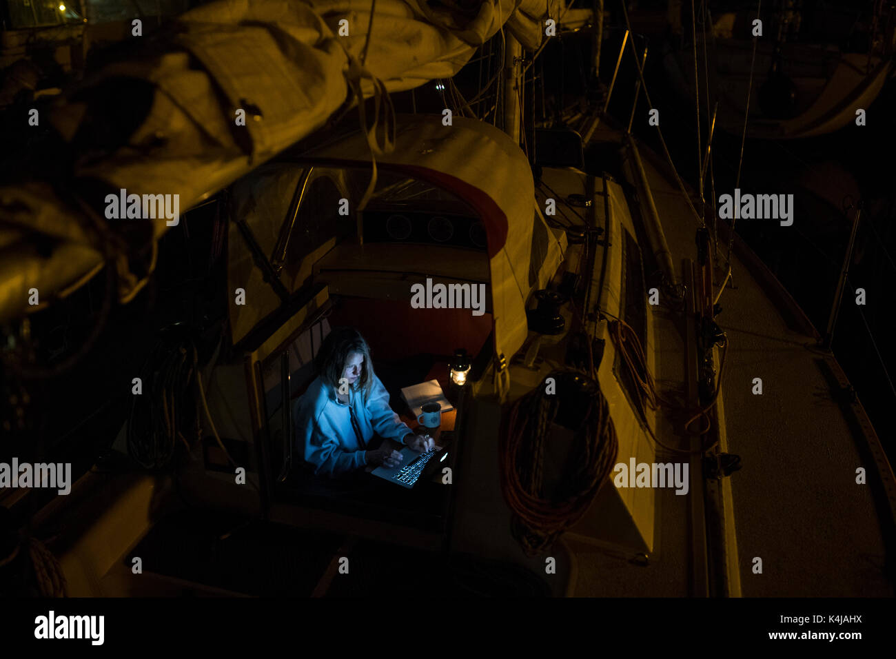 Frau, die Computer in die Limousine von einem Segelboot am Abend Stockfoto