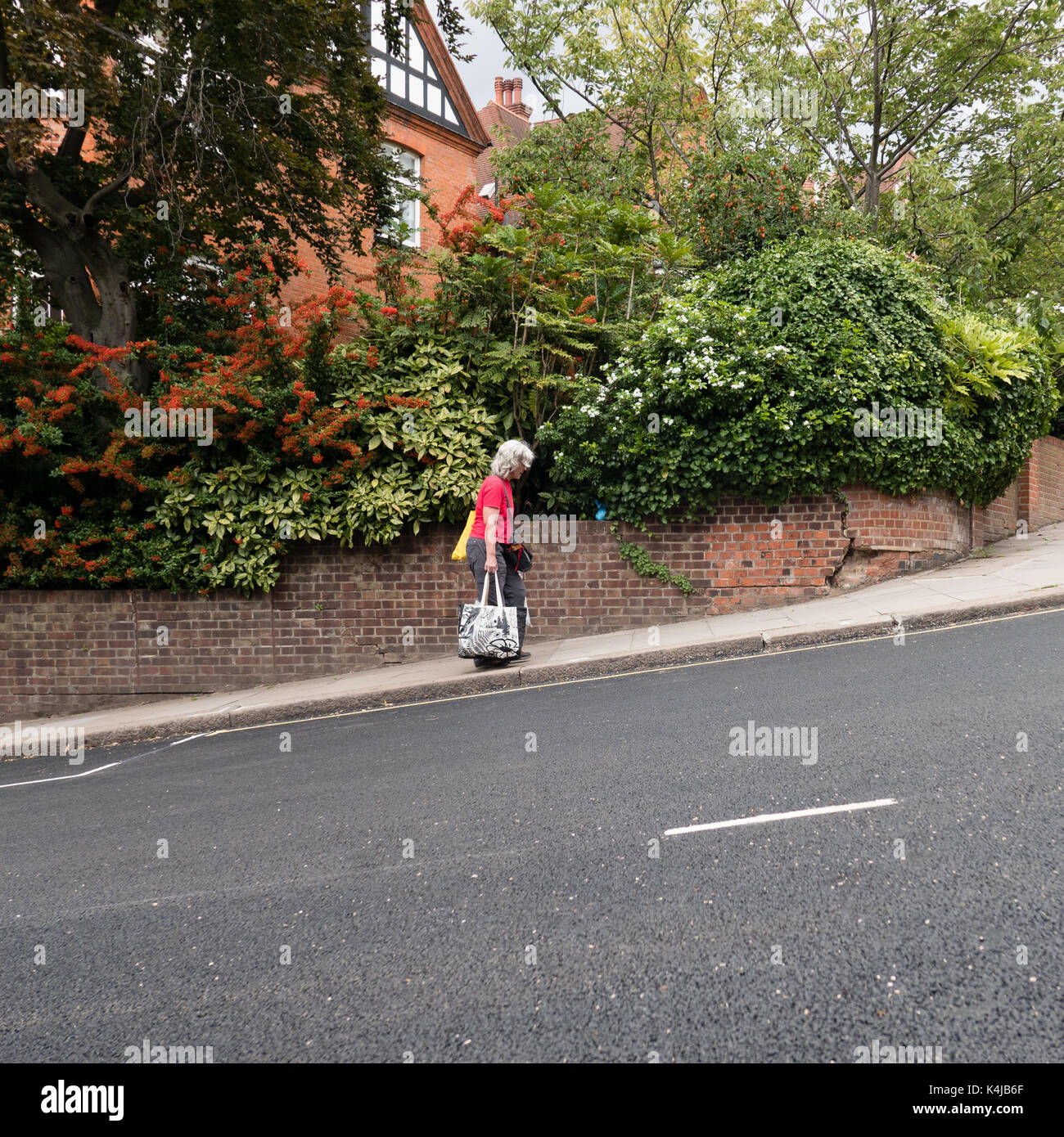 Eine Frau, die sich Shopping einen steilen Hügel in Hampstead, London Stockfoto