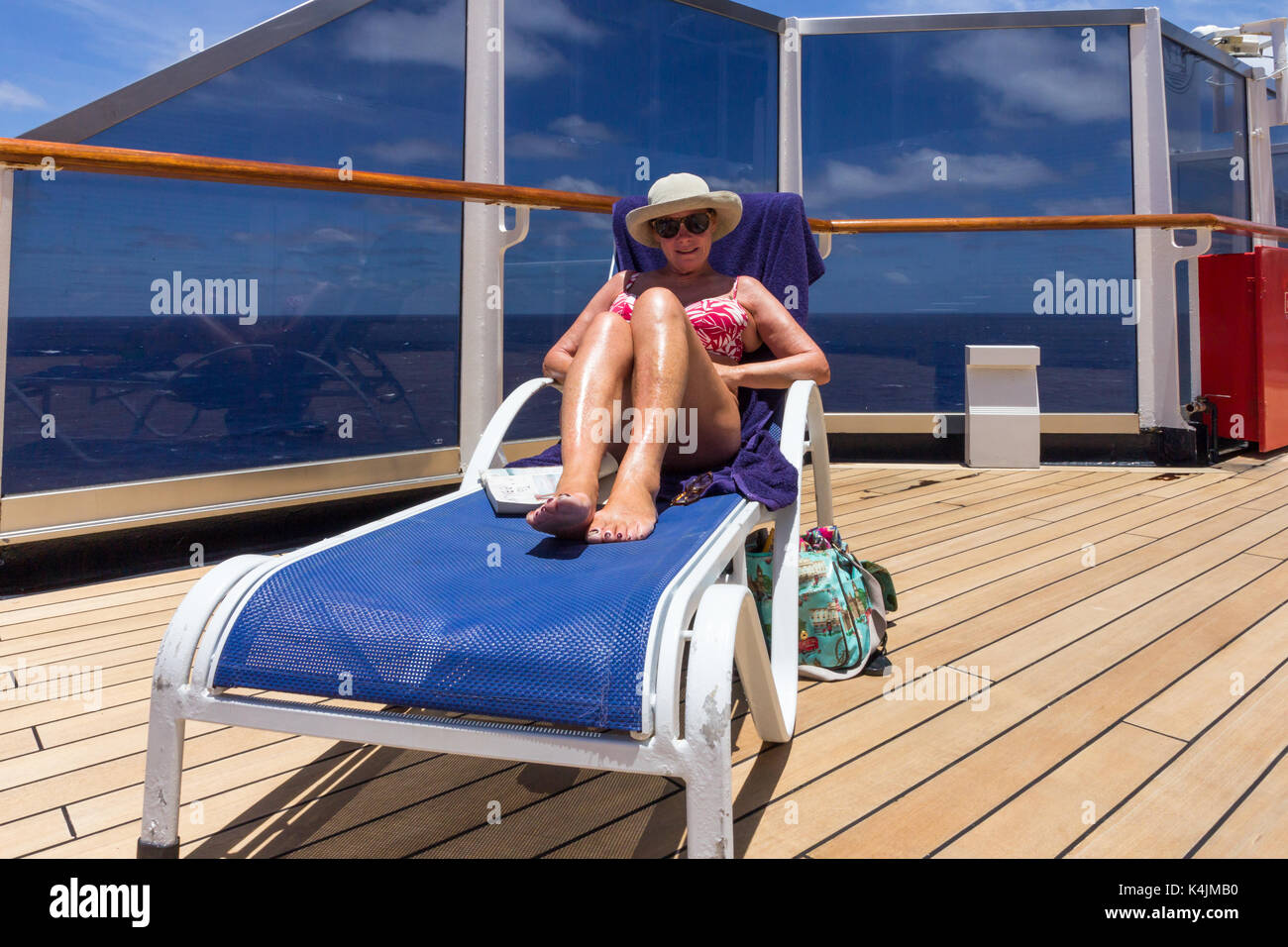 Ältere Frau auf einer Sonnenliege entspannen an Bord eines Kreuzfahrtschiffes Stockfoto