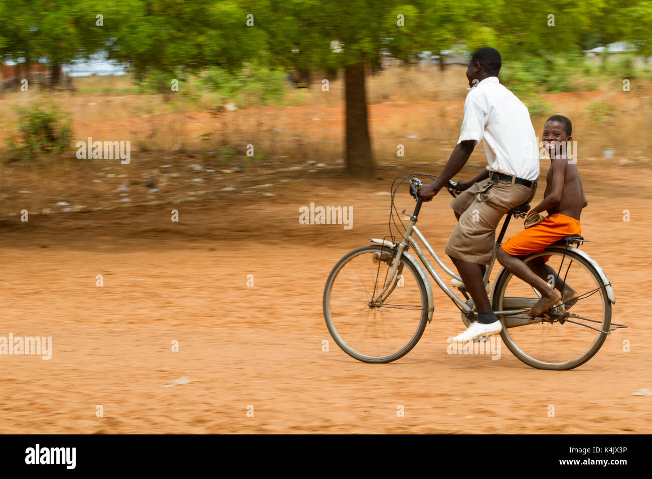 Eine Schule Junge bekommt einen Aufzug Home auf der Rückseite ein Fahrrad, Ghana, West Afrika, Afrika Stockfoto