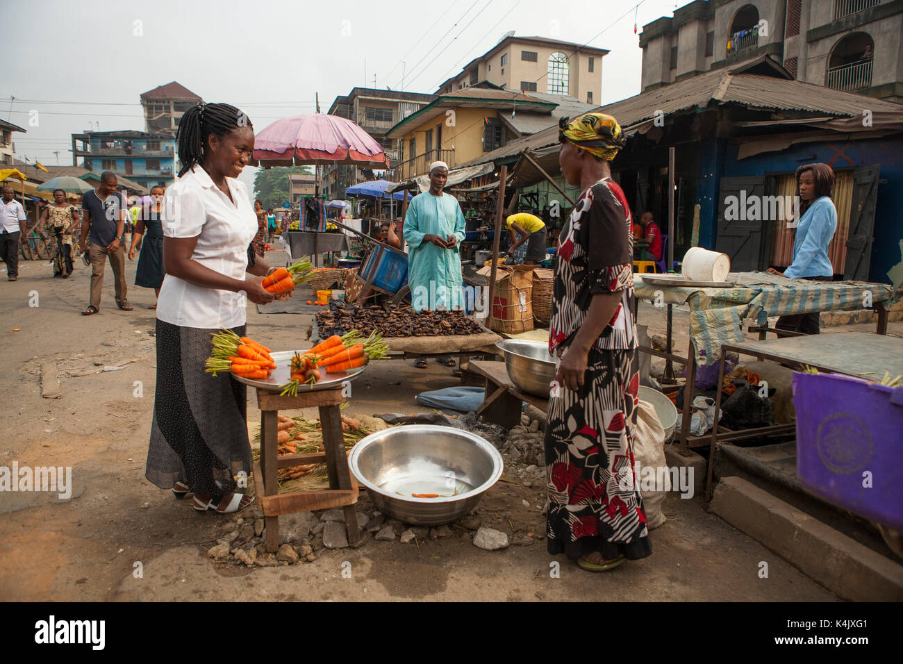 Eine Frau kaufen Karotten auf dem Markt in Nigeria, Westafrika, Afrika Stockfoto