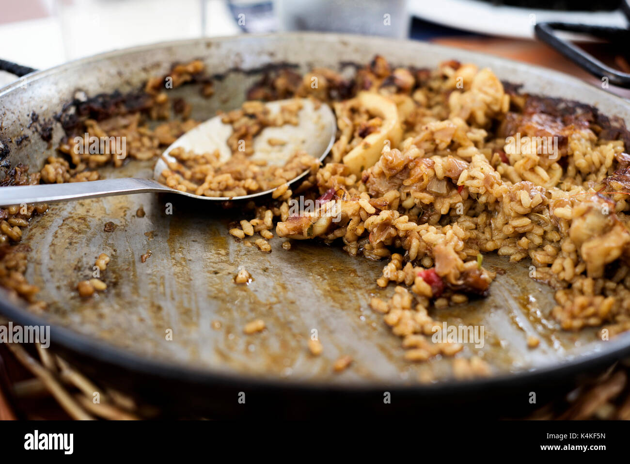 Nahaufnahme eines paellera, die Paella Pfanne, mit einige spanische Paella und ein Löffel, auf einem Tisch während der Mittagspause Stockfoto