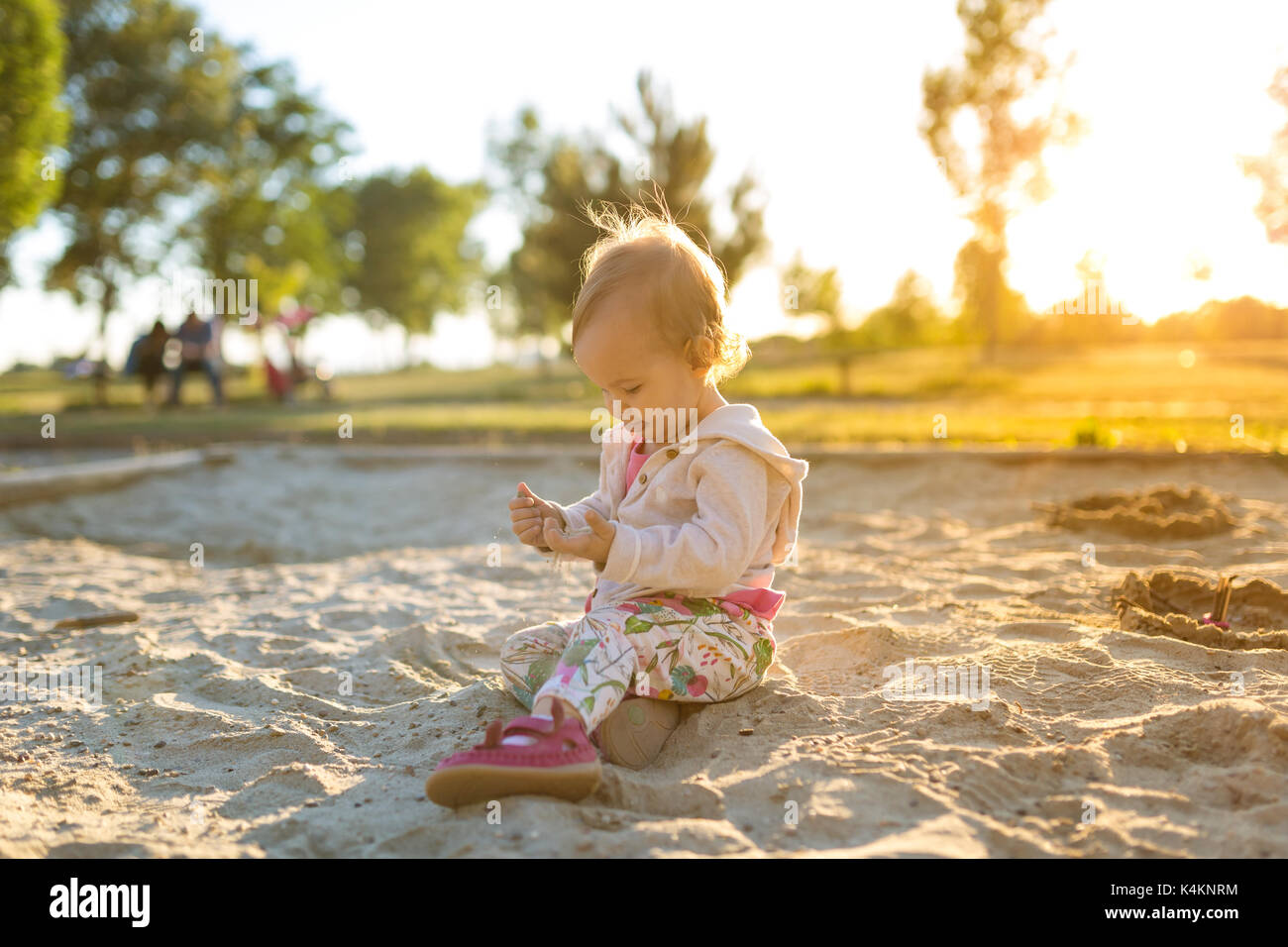 15 Monate altes Baby Mädchen spielen im Sandkasten im Sonnenuntergang Stockfoto