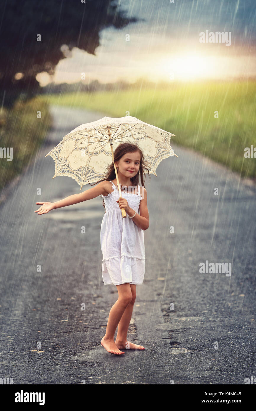 Happy girl Verstecken von der Regen unter dem Dach Stockfoto