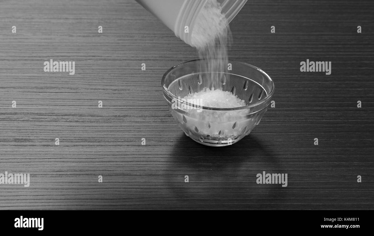 Zucker in eine Schüssel geben Stockfoto