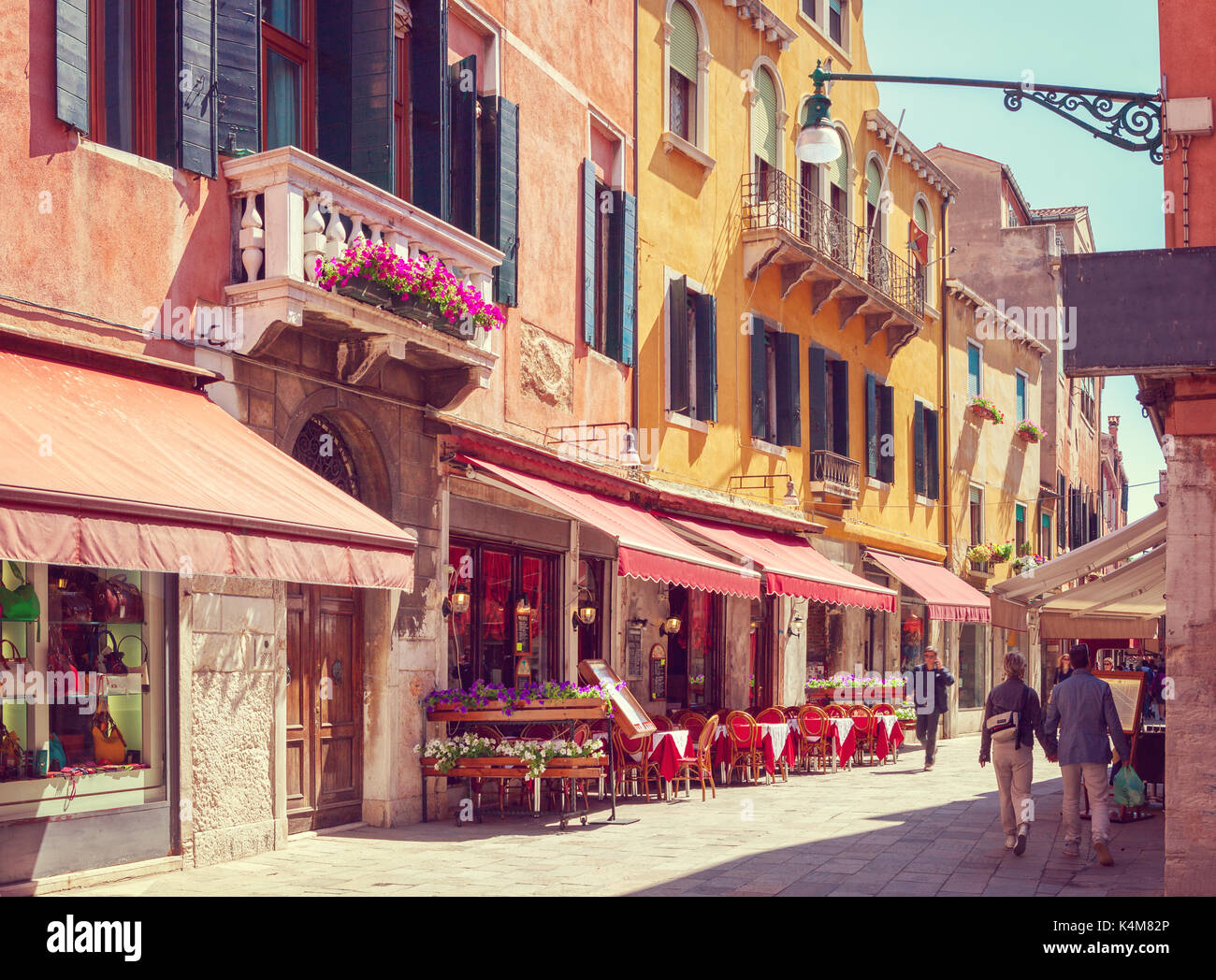 Bunte gemütliche Straße bei Tabellen mit Cafe an einem sonnigen Morgen, Venedig, Italien. Getonten Bild Stockfoto