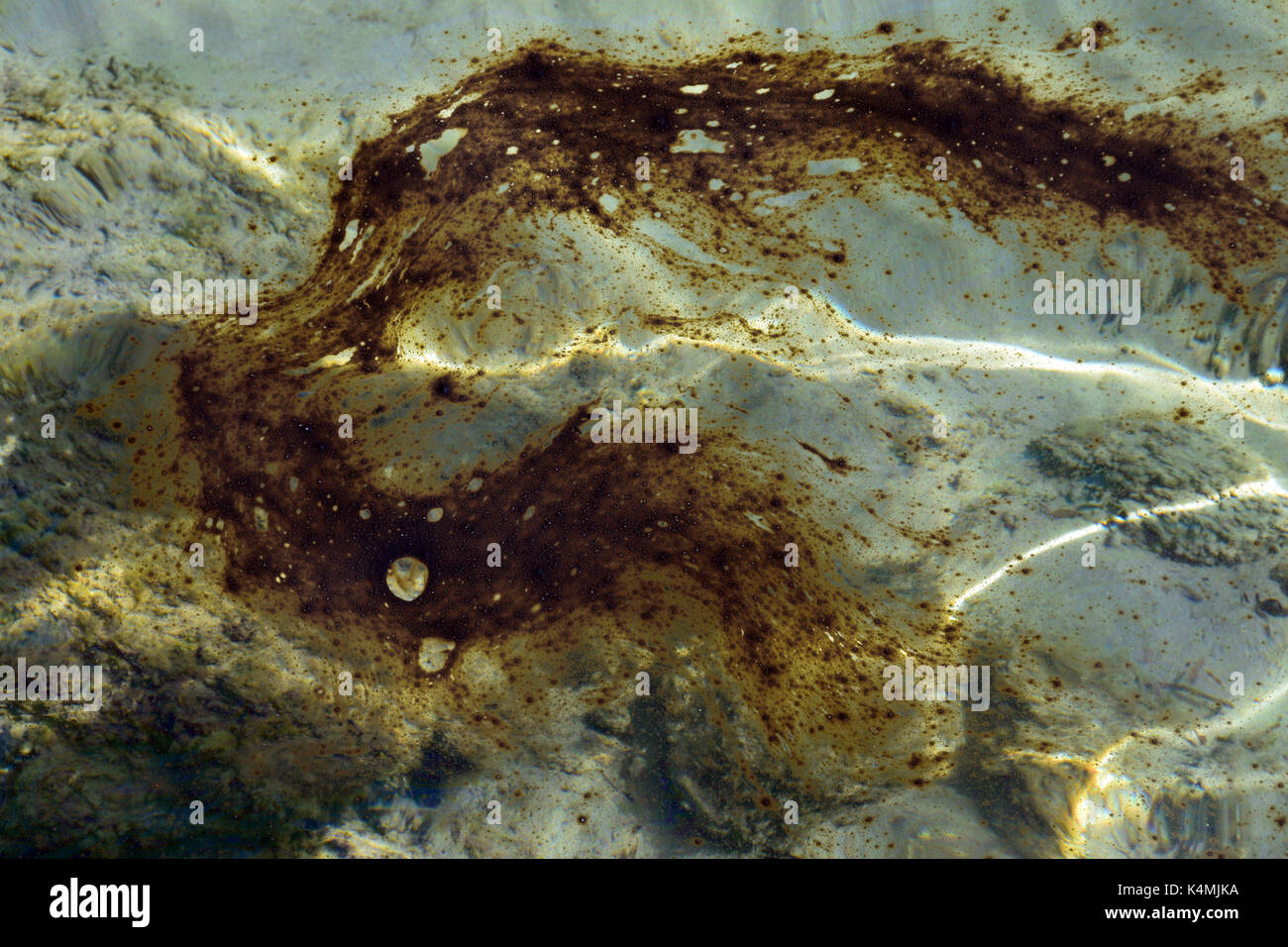 Nahaufnahme von teeröl Substanz schwimmt auf Wasser Oberfläche. Verschmutzten Strand. Stockfoto