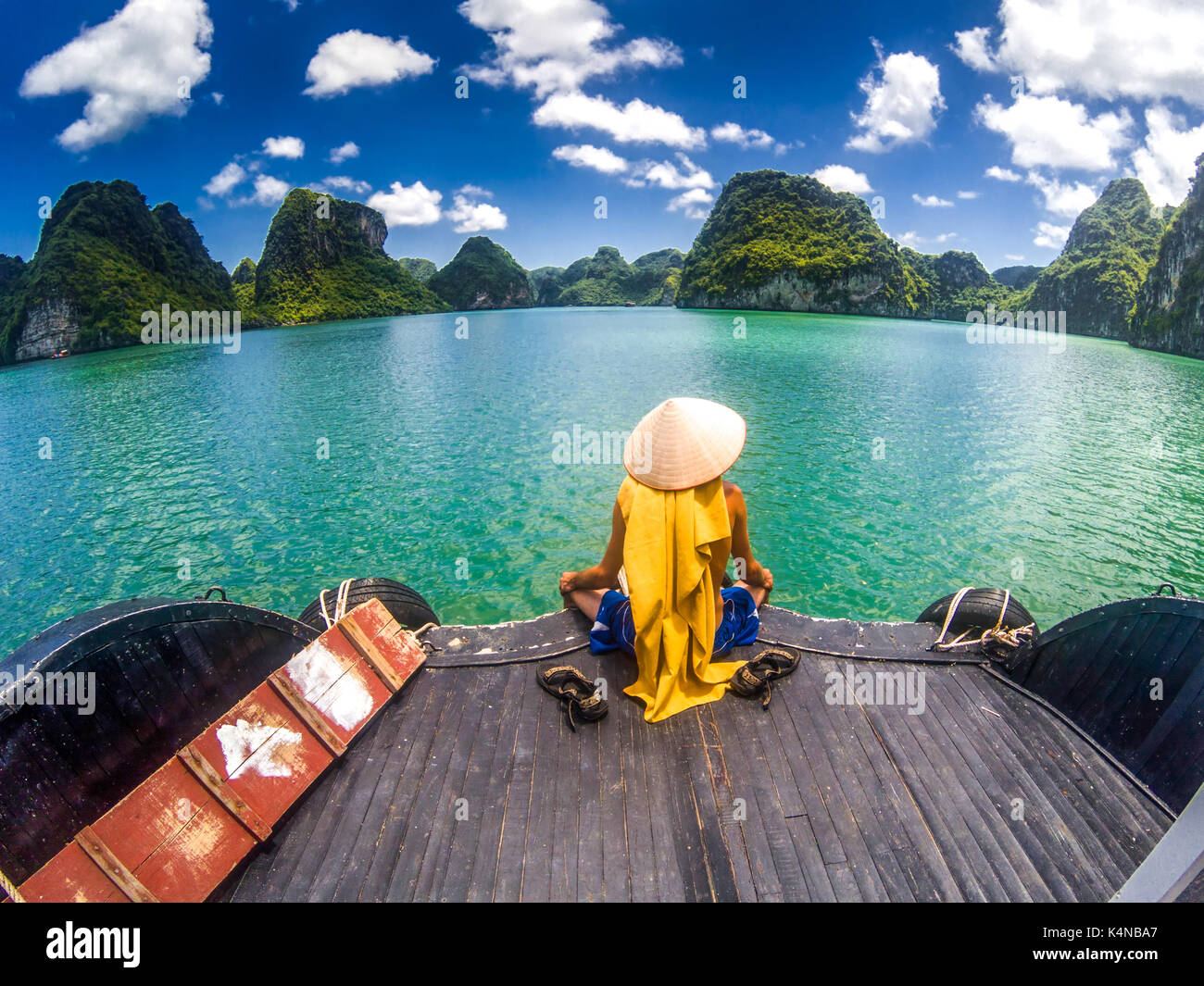 Mann mit einem vietnamesischen hat genießen die magnifiecent Anblick von Ha Long Bay Kalksteinfelsen an einem schönen sonnigen Tag während einer Bootsfahrt, UNESCO worl Stockfoto