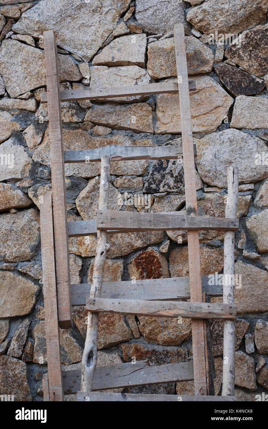 Rustikale Holzleitern gegen eine Mauer aus Stein Stockfoto