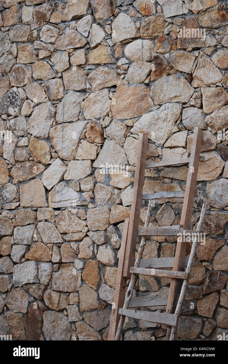 Rustikale Holzleitern gegen eine Mauer aus Stein Stockfoto