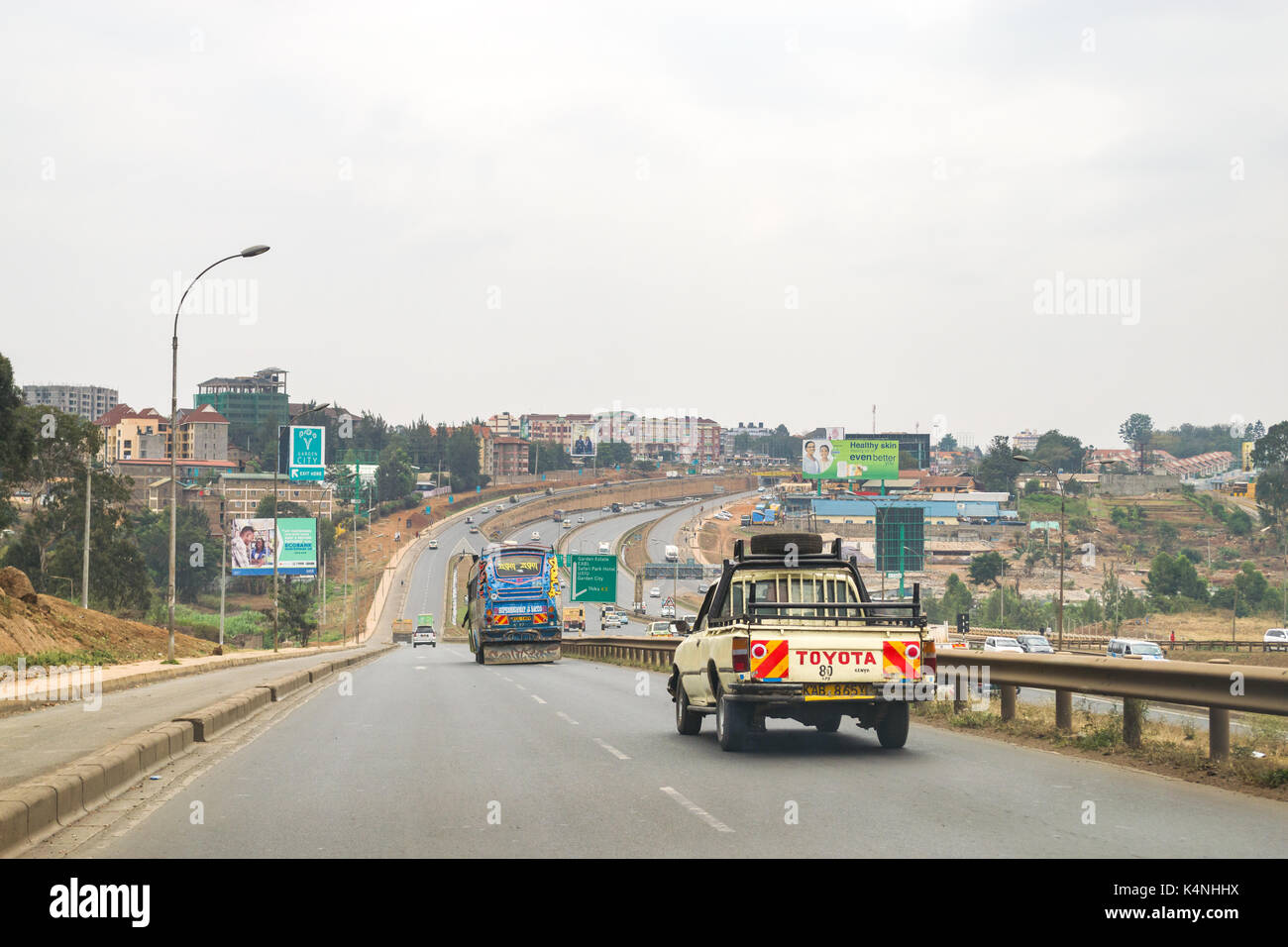 Fahrzeuge fahren auf Zubringerstraße zur Autobahn Thika mit Verkehr auf Autobahn, Nairobi, Kenia Stockfoto