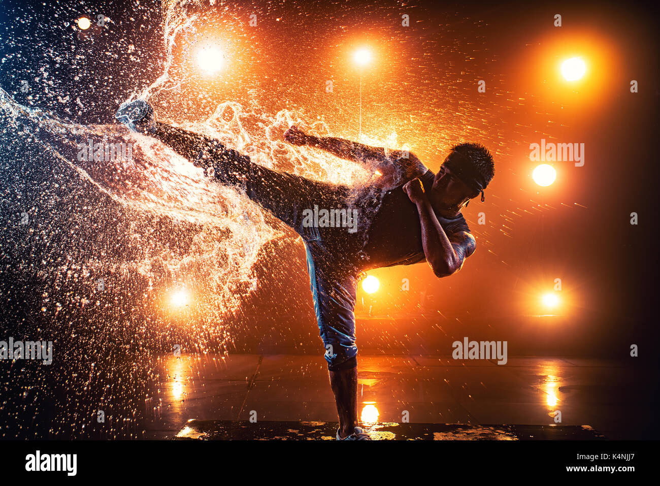Junger Mann Breakdancer, Kick auf Spritzwasser. Tattoo am Körper. Stockfoto